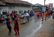 Children help their teacher Deep Narayan Nayak pull a rack of books during their open-air classes outside the houses with the walls converted into black boards at Joba Attpara village