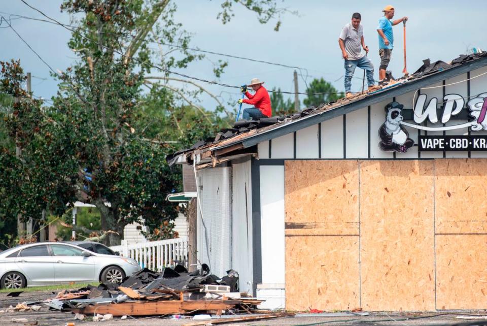 Workers clear off the roof of a smoke shop in Moss Point on Tuesday, June 20, 2023, after a tornado tore through the town on Monday.