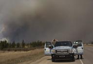 People stop to take photos of a wildfire south of Fort McMurray, Alta., on Thursday May 5, 2016. An ever-changing, volatile situation is fraying the nerves of residents and officials alike as a massive wildfire continues to bear down on the Fort McMurray area of northern Alberta. THE CANADIAN PRESS/Jason Franson