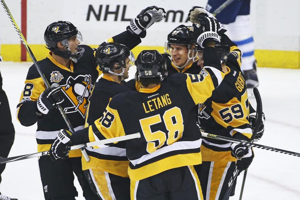 Pittsburgh Penguins' Sidney Crosby (87) is surrounded by teammates after Crosby assisted on a goal by Chris Kunitz, for the 1,000th point of his NHL career, during the first period of the team's hockey game against the Winnipeg Jets in Pittsburgh, Thursday, Feb. 16, 2017. (AP Photo/Gene J. Puskar)