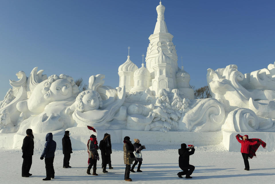 Tourists take pictures in front of a snow sculpture ahead of the 13th Harbin Ice and Snow World in Harbin, Heilongjiang province December 26, 2011. The Harbin International Ice and Snow Festival will be officially launched on January 5, 2012. REUTERS/Sheng Li (CHINA - Tags: ENVIRONMENT SOCIETY)
