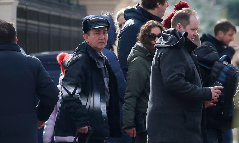 People carrying luggage leave the Russian embassy to board a van bearing diplomatic plates.