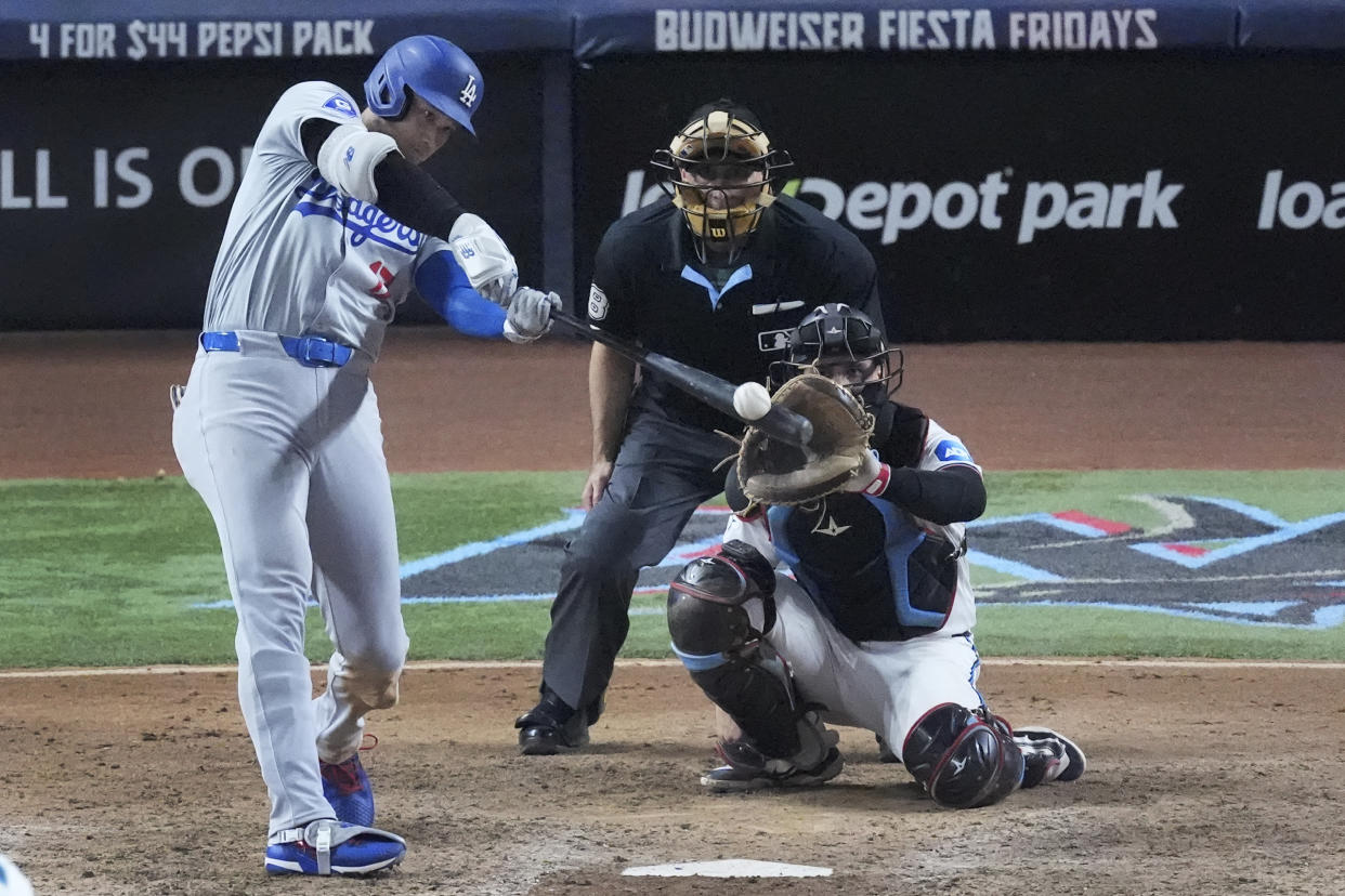 Los Angeles Dodgers' Shohei Ohtani, of Japan, hits a home run, scoring Max Muncy and Chris Taylor, during the ninth inning of a baseball game against the Miami Marlins, Thursday, Sept. 19, 2024, in Miami. (AP Photo/Wilfredo Lee)