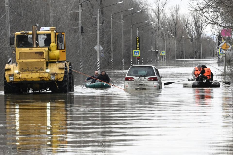 People use rubber boats to cross a flooded street in Orsk (AP)