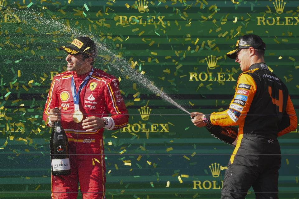 Ferrari driver Carlos Sainz of Spain is sprayed in champagne after winning the Australian Formula One Grand Prix by McLaren driver Lando Norris, right, of Britain at Albert Park, in Melbourne, Australia, Sunday, March 24, 2024. (AP Photo/Scott Barbour)