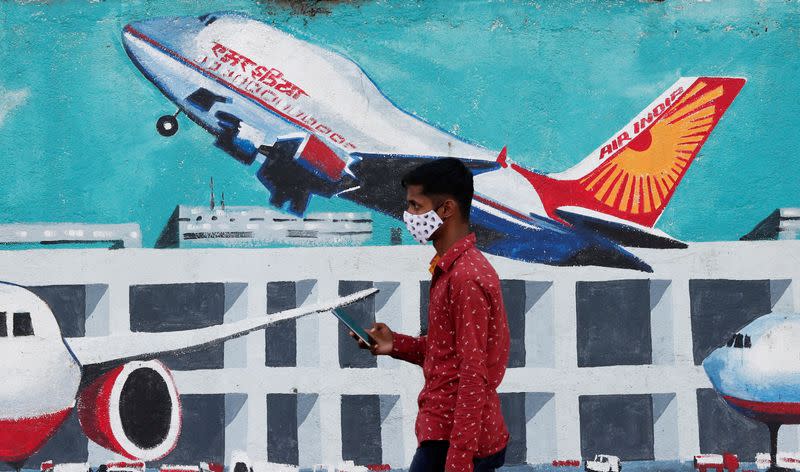 FILE PHOTO: A man walks past a mural of Air India airlines on a street in Mumbai