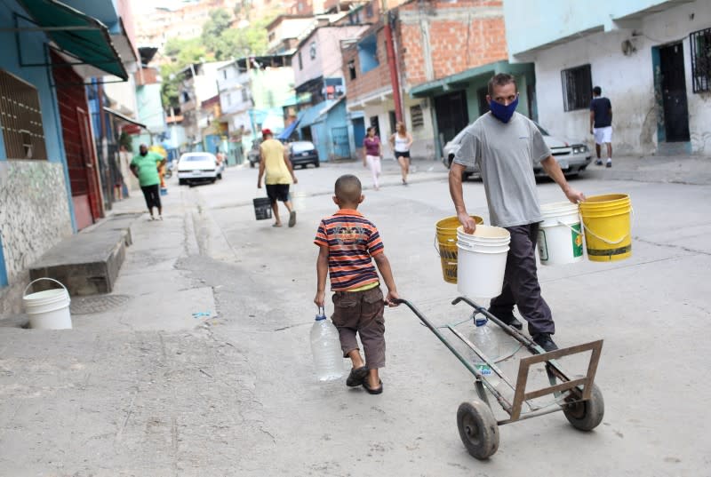 People walk with plastic containers near an unknown water source in the low-income neighbourhood of Petare amid the coronavirus disease (COVID-19) outbreak in Caracas