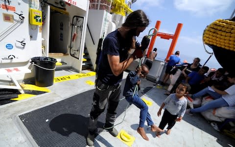 A migrant child plays with a member of the crew on board the MV Aquarius rescue ship run by SOS Mediterranee organisation and Doctors Without Borders during a search and rescue (SAR) operation in the Mediterranean Sea, off the Libyan Coast, August 12  - Credit: GUGLIELMO MANGIAPANE/REUTERS