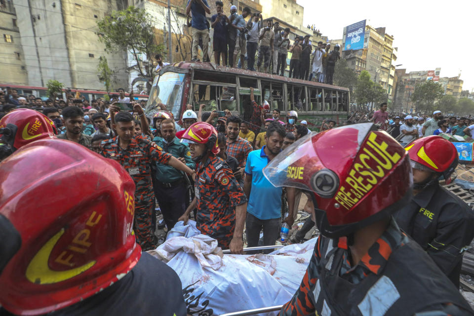 Fire officials carry a body of a victim after an explosion in a commercial building, in Dhaka, Bangladesh, Tuesday, March 7, 2023. An explosion in a seven-story commercial building in Bangladesh's capital has killed at least 14 people and injured dozens. Officials say the explosion occurred in a busy commercial area of Dhaka. (AP Photo/Abdul Goni)