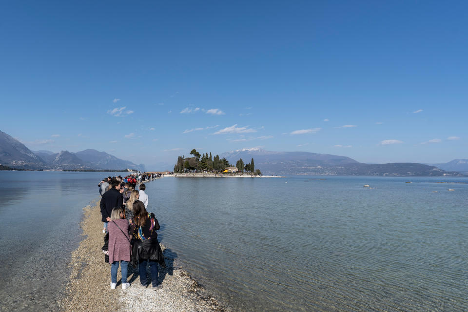 Menschen spazieren von Punta Belvedere nach Isola dei Conigli über den Gardasee aufgrund des ungewöhnlich niedrigen Wasserstands. 