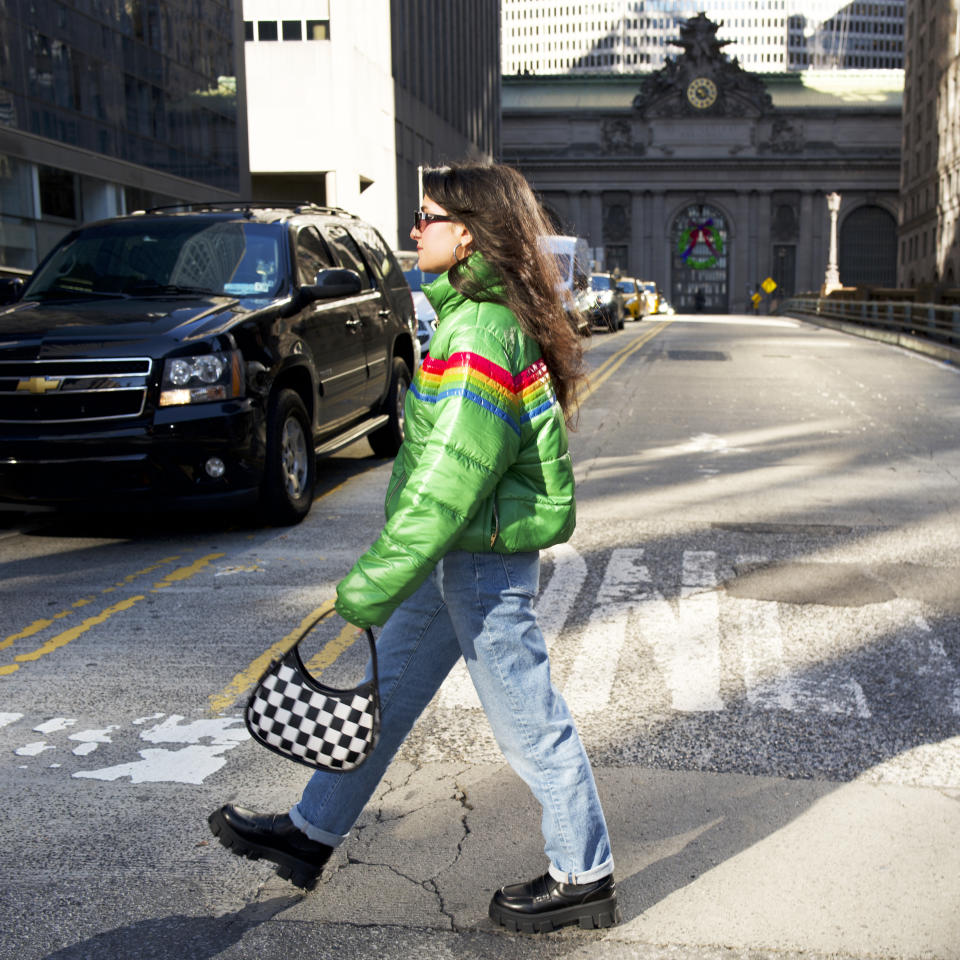 woman crossing street holding a small shoulder bag 