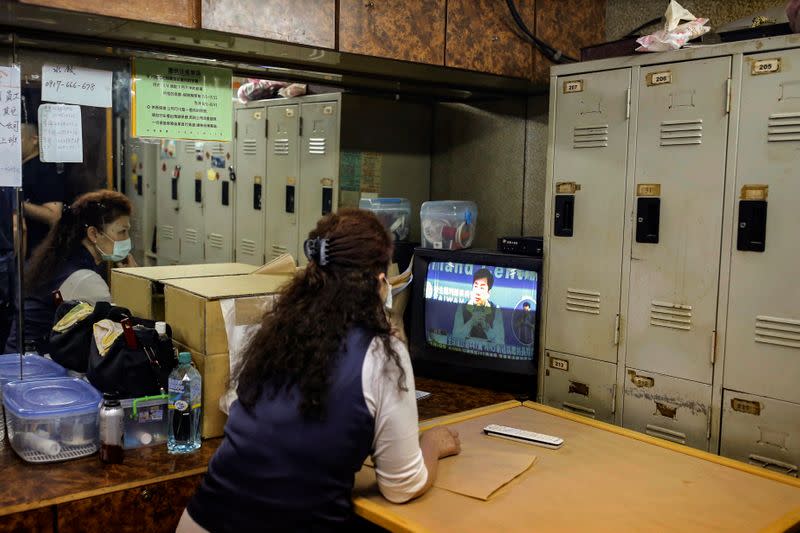 A staff watches a TV broadcast of daily updates on the coronavirus disease (COVID-19) from Taiwan's Centers for Disease Control and Prevention while waiting for customers at the break room of a massage parlour in Taipei