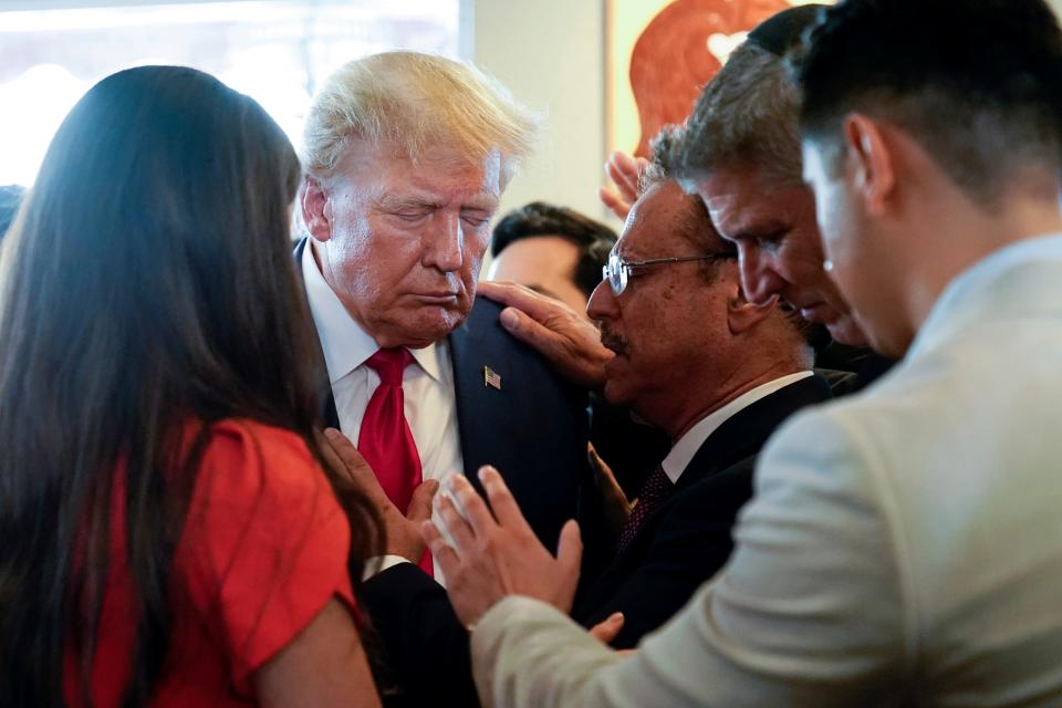 Former President Donald Trump prays with pastor Mario Bramnick, third from right, and others at Versailles restaurant on June 13, 2023, in Miami.