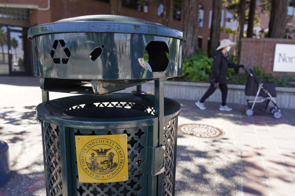 A woman walks past a Renaissance trash can that has been used for nearly 20 years in San Francisco, on July 26, 2022. As a replacement for the Renaissance trash can, city officials have deployed custom-made trash cans that took more than 3 years to design and produce, including one prototype that cost taxpayers more than $20,000. Now they are asking residents for feedback. (AP Photo/Eric Risberg)