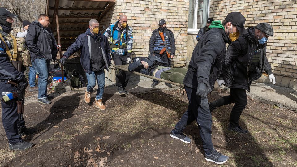 Ukrainian servicemen carry a dead body found in a basement in the town of Bucha on April 4. - Marko Djurica/Reuters