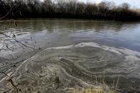 In this Wednesday, Feb. 5, 2014 photo, signs of coal ash swirl in the water in the Dan River in Danville, Va. Duke Energy estimates that up to 82,000 tons of coal ash has been released from a break in a 48-inch storm water pipe at the Dan River Power Plant in Eden N.C.Over the last year, environmental groups have tried three times to use the federal Clean Water Act to force Duke Energy to clear out leaky coal ash dumps. Each time, the N.C. Department of Environment and Natural Resources has effectively halted the lawsuit by intervening at the last minute to assert its own authority to take enforcement action. In two cases, the state has proposed modest fines but no requirement that the nation’s largest electricity provider actually clean up the coal ash ponds. The third case is pending. (AP Photo/Gerry Broome)