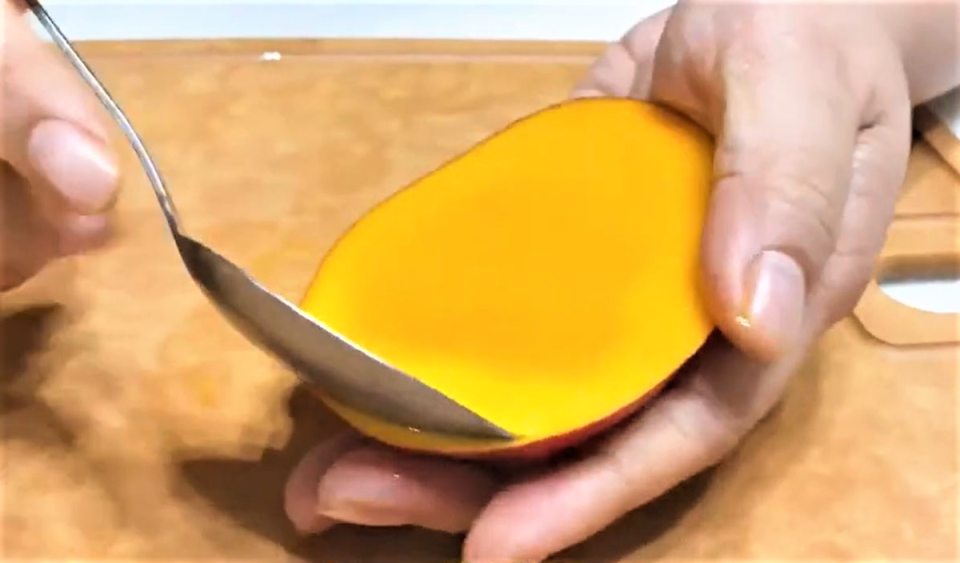 大湯匙從下緣順著芒果的弧度切入。