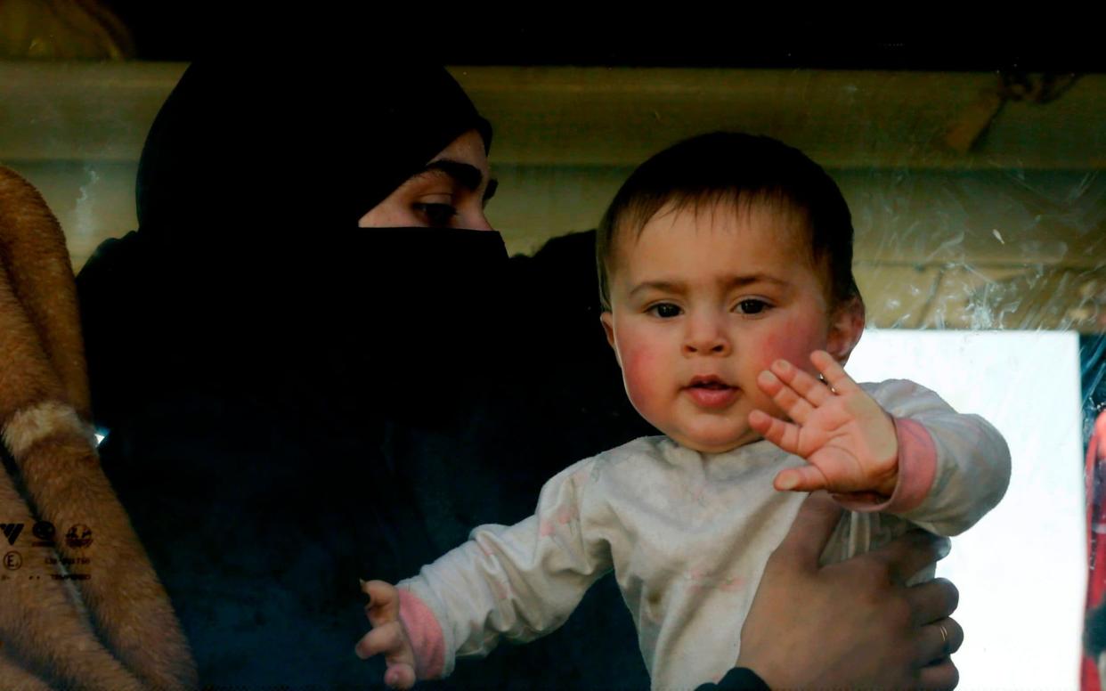 A baby waves at the window of a bus as Syrian civilians and rebel fighters evacuated from Eastern Ghouta arrive in a government-held area - AFP