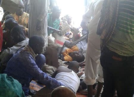 Injured people are comforted at the site after a bombing attack of an internally displaced persons camp in Rann, Nigeria. MSF/Handout via Reuters