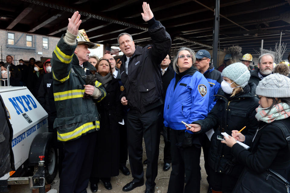 FILE - In this March 13, 2014, file photo, New York City Mayor Bill de Blasio, center, talks with first responders near the site of a gas leak-triggered fatal explosion in East Harlem, in New York. De Blasio’s first 100 days as mayor of NYC were marked in nearly equal measures by accomplishing campaign goals and committing political blunders. Observers believe he effectively projected leadership and compassion, devoting city resources to helping those impacted by the blast. (AP Photo/The Daily News, Marcus Santos, Pool, File)