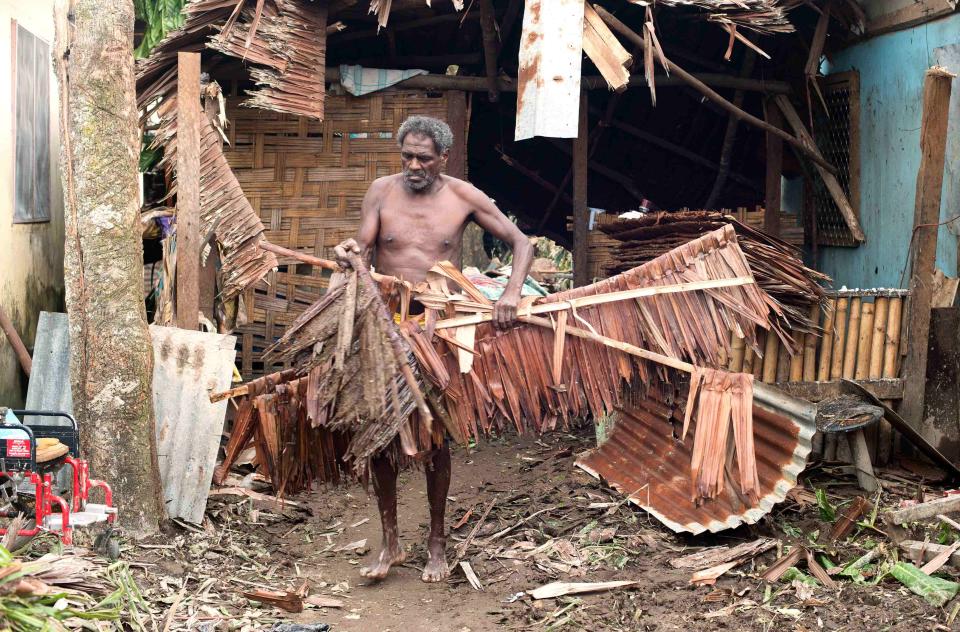 A local resident moves debris from near his damaged home after Cyclone Pam hit Port Vila, the capital city of the Pacific island nation of Vanuatu