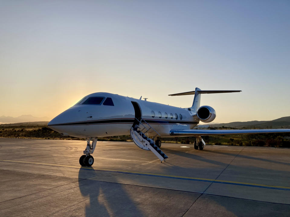 Private jet parked on a runway during sunrise, with no people visible