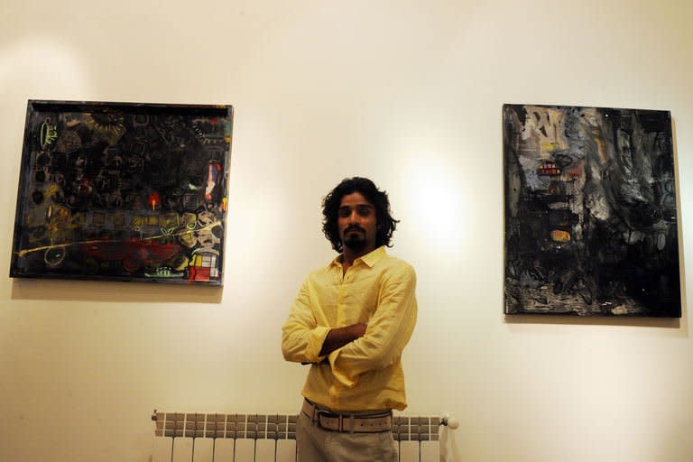 Pakistani artist Tahir Ali poses with his paintings at the Rohtas Art Gallery in Islamabad, December 12, 2012