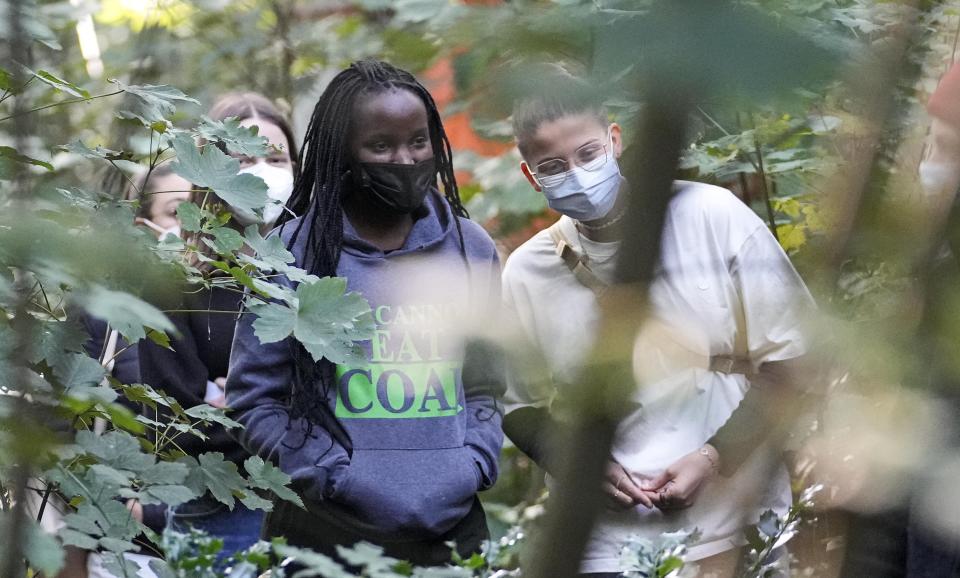 Climate activists Vanessa Nakate from Uganda and Leonie Bremer of the German Fridays for Future movement, right, visit activists in a forest near the Garzweiler open-cast coal mine in Keyenberg, western Germany, Saturday Oct. 9, 2021. Garzweiler, operated by utility giant RWE, has become a focus of protests by people who want Germany to stop extracting and burning coal as soon as possible. (AP Photo/Martin Meissner)