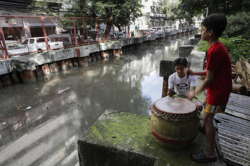 Carlo Sicat, left, uses his smartphone to record the drum beat while his son Gian practices after a year of almost not playing due to pandemic restrictions at a creekside slum at Manila's Chinatown, Binondo, Philippines on Feb. 4, 2021. The Dragon and Lion dancers won't be performing this year after the Manila city government banned the dragon dance, street parties, stage shows or any other similar activities during celebrations for Chinese New Year due to COVID-19 restrictions leaving several businesses without income as the country grapples to start vaccination this month. (AP Photo/Aaron Favila)