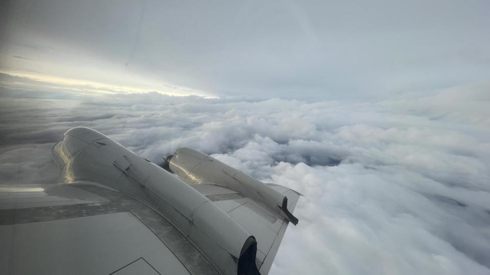     A large swirling storm can be seen off the wing of an aircraft. 