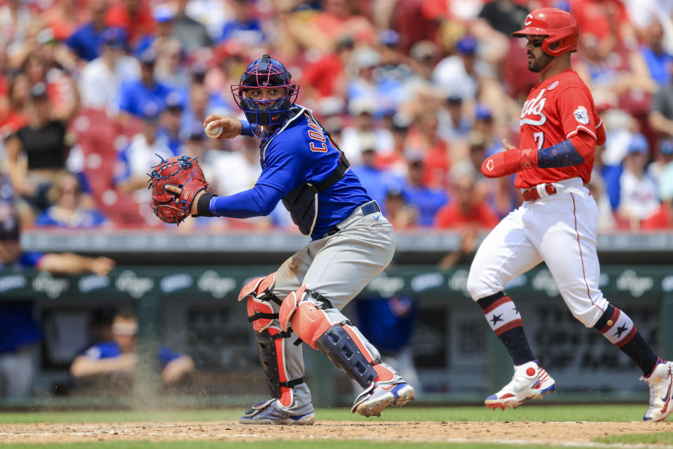 Chicago Cubs' Willson Contreras, left, looks to throw to first base as he forces out Cincinnati Reds' Eugenio Suarez at home plate during the seventh inning of a baseball game in Cincinnati, Sunday, July 4, 2021. (AP Photo/Aaron Doster)