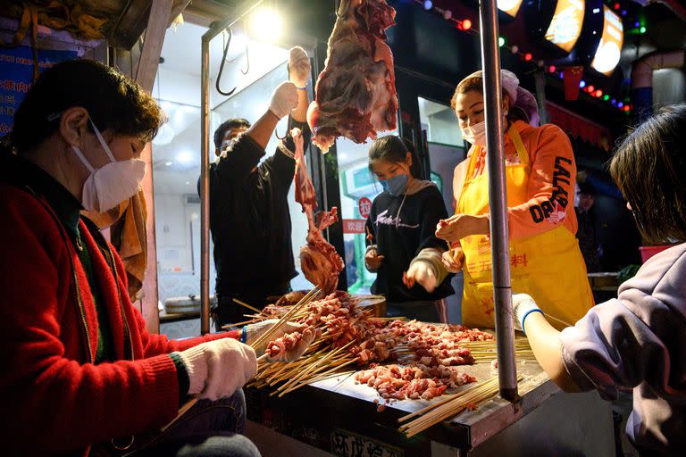 Los trabajadores que usan mascarillas hacen una barbacoa en un mercado en Wuhan, en la provincia central china de Hubei, el 4 de abril de 2020.