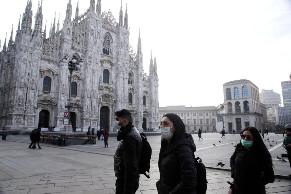 People wearing sanitary masks walk past the Duomo gothic cathedral in Milan, Italy, Sunday, Feb. 23, 2020. A dozen Italian towns saw daily life disrupted after the deaths of two people infected with the virus from China and a pair of case clusters without direct links to the outbreak abroad. A rapid spike in infections prompted authorities in the northern Lombardy and Veneto regions to close schools, businesses and restaurants and to cancel sporting events and Masses. (AP Photo/Luca Bruno)