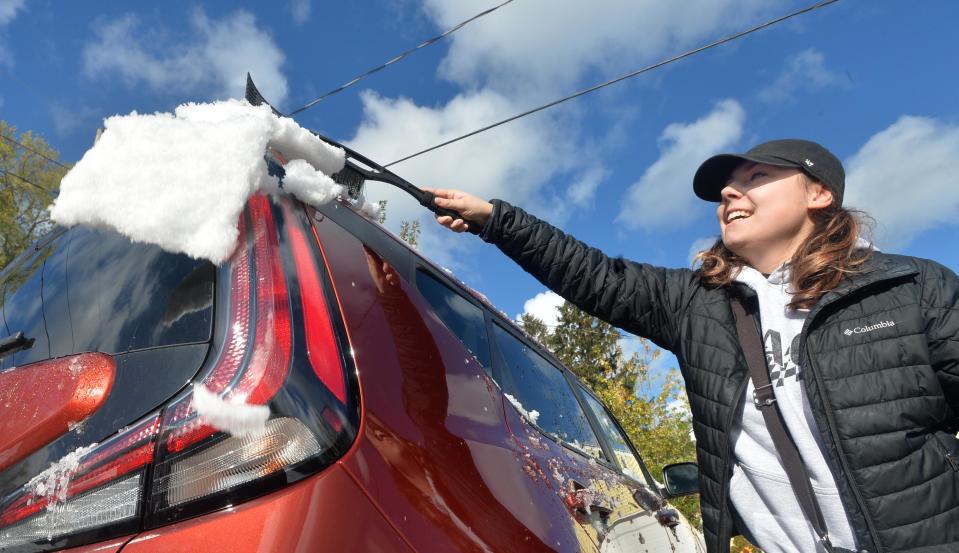 Isabella Stefanelli, 23, wipes snow from atop her new car on Wednesday in Millcreek Township after the first snow of the season fell Tuesday night on the Erie area.