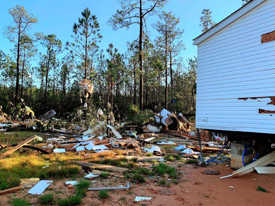 Debris hangs in the trees outside a trailer home that was cut in half as a tornado touched down in Vancleave, Mississippi.