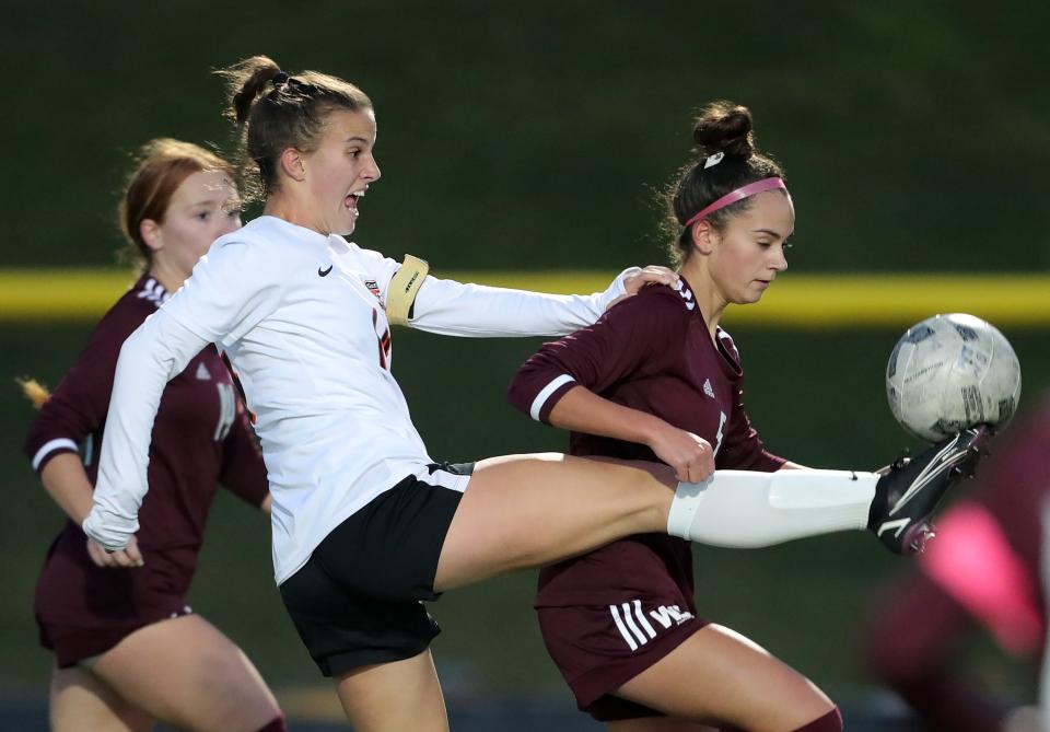 Green's Jamie Duskey, left, kicks the ball over Walsh's Hannah Pachan during the first half of a Division I district championship soccer game at NDCL, Thursday, Oct. 27, 2022, in Chardon, Ohio.