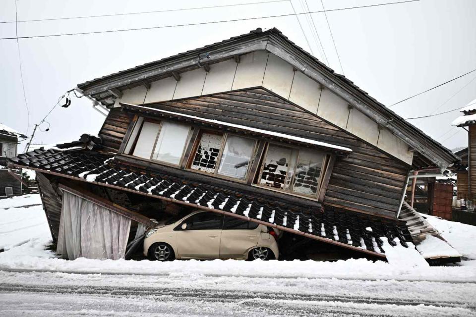 <p>PHILIP FONG/AFP via Getty</p> A damaged car lies underneath a collapsed building at Shika town in Hakui District, Ishikawa Prefecture on Jan. 8, 2024 after a major 7.5 magnitude earthquake