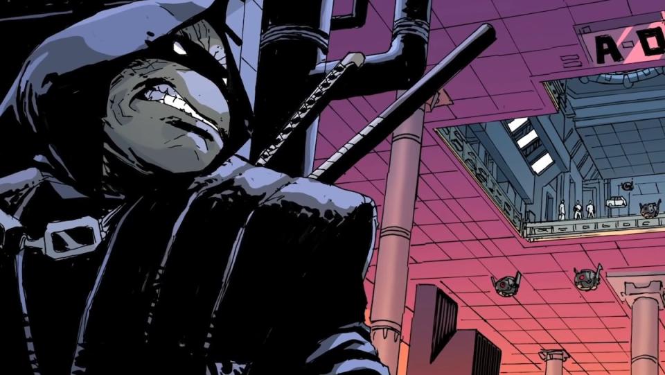 A page from TMNT: The Last ROnin comic featuring the Ninja Turtle in a black mask and hood hiding behind a wall in a large factory room