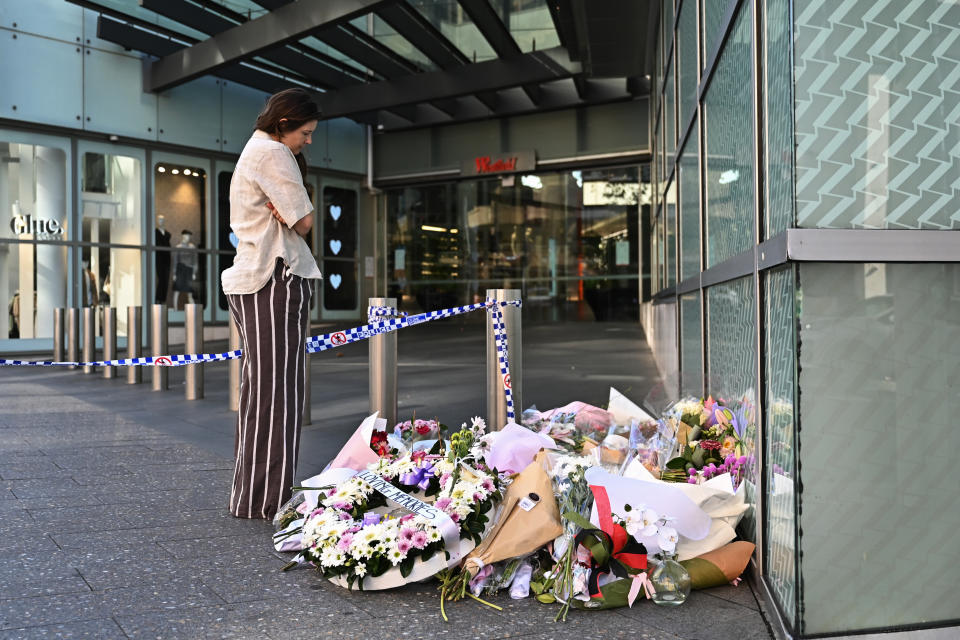 A person looks at floral tributes left at the entrance to Westfield Bondi Junction shopping centre after the attack. 