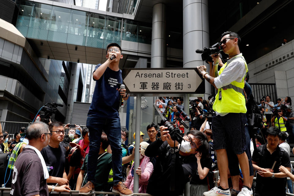 FILE - In this June 21, 2019, file photo, pro-democracy activist Joshua Wong, center left, speaks as protesters surround the police headquarters in Hong Kong. Demosisto, a pro-democracy group in Hong Kong, posted on its social media accounts that well-known activist Wong had been pushed into a private car around 7:30 a.m. Friday, Aug. 30, 2019 and was taken to police headquarters. It later said another member, Agnes Chow, had also been arrested, at her home. (AP Photo/Vincent Yu, File)