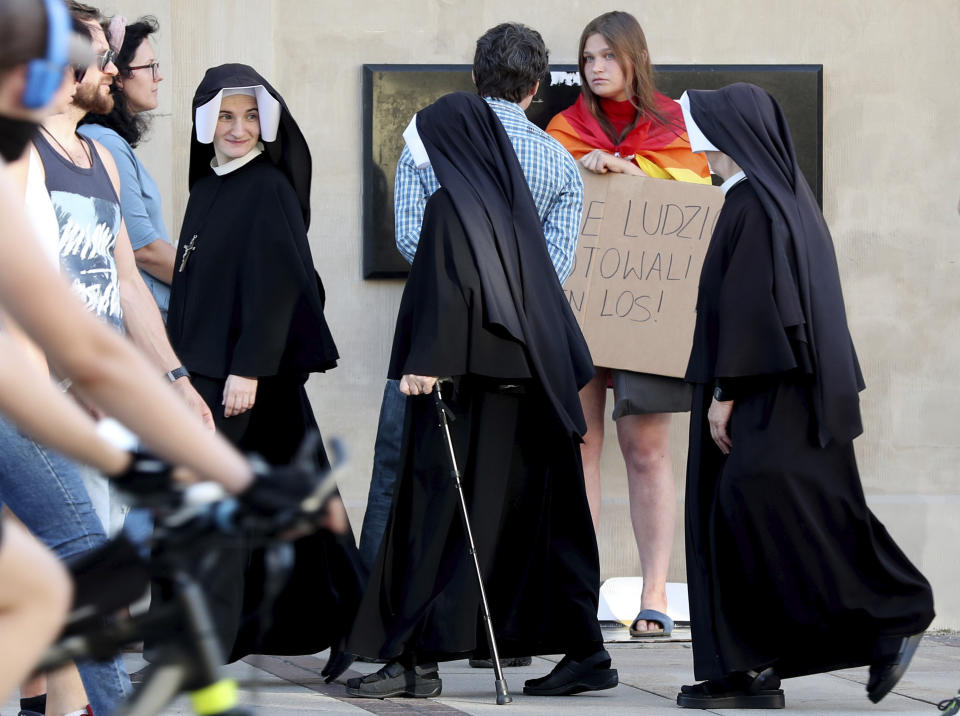 In this Aug. 2, 2020 taken photo nuns pass a LGBT protester in Warsaw, Poland. LGBT people are choosing to leave Poland amid rising homophobia promoted by President Andrzej Duda and other right-wing populist politicians in power. On Thursday, with Duda to be sworn in for a second term as president, some LGBT people have already left Poland or are making plans to leave. (AP Photo/Czarek Sokolowski)