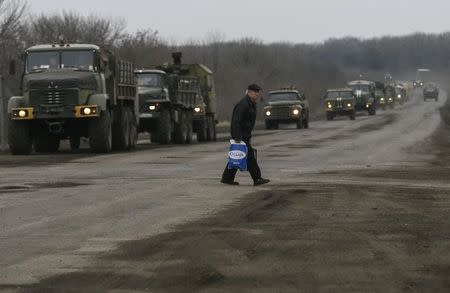 A local resident walks as a convoy of Ukrainian armed forces stand on the road near Artemivsk, eastern Ukraine, March 3, 2015. REUTERS/Gleb Garanich