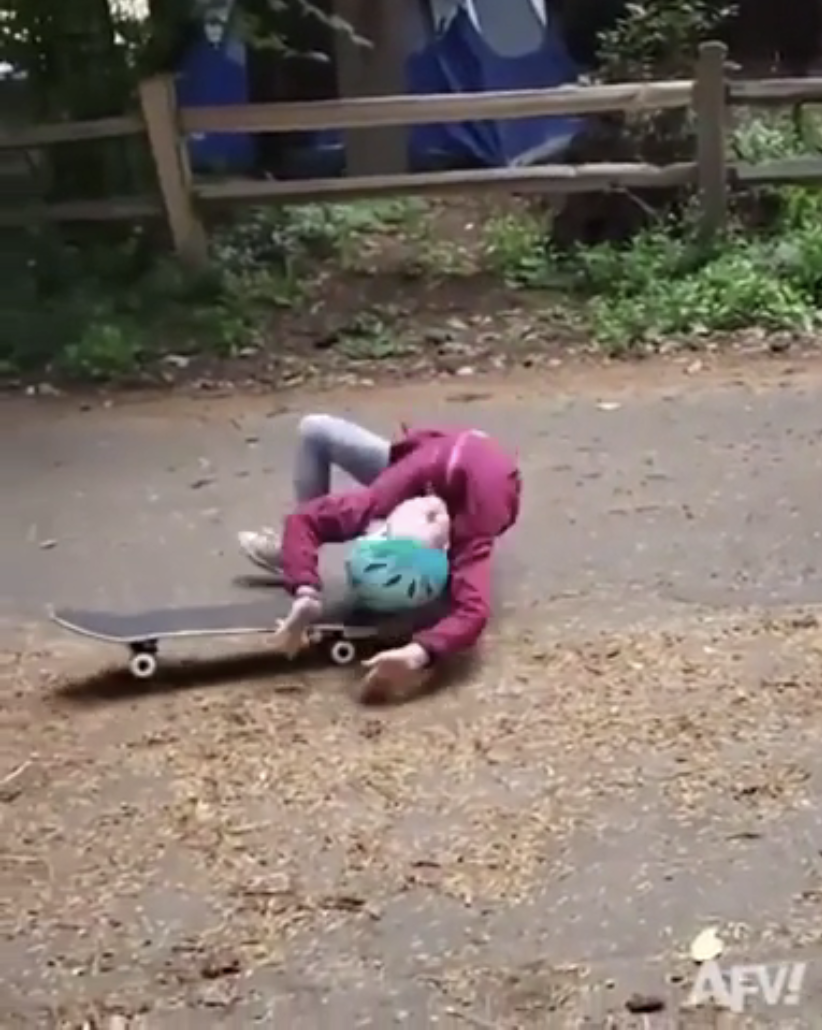 Person in helmet and jacket has fallen off a skateboard onto the ground