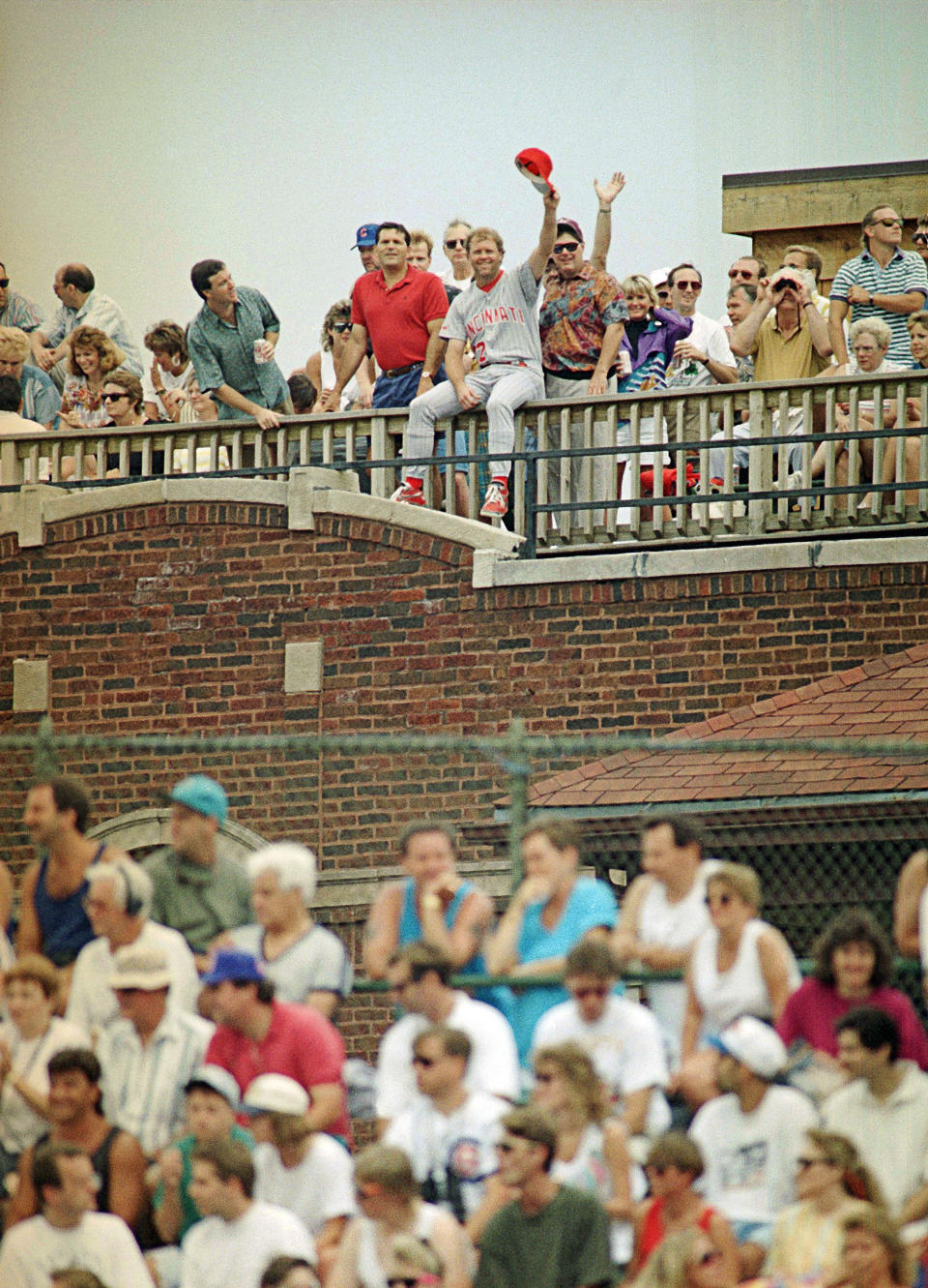 FILE - Cincinnati Reds pitcher Tom Browning, center, waves from a roof on Sheffield Avenue across from Wrigley Field in Chicago as he watches the Reds' game against the Chicago Cubs, July 7, 1993. Browning was not scheduled to pitch. Browning, an All-Star pitcher who threw the only perfect game in Cincinnati Reds history and helped them win a World Series title, died on Monday, Dec. 19, 2022. He was 62. (AP Photo/John Swart, File)