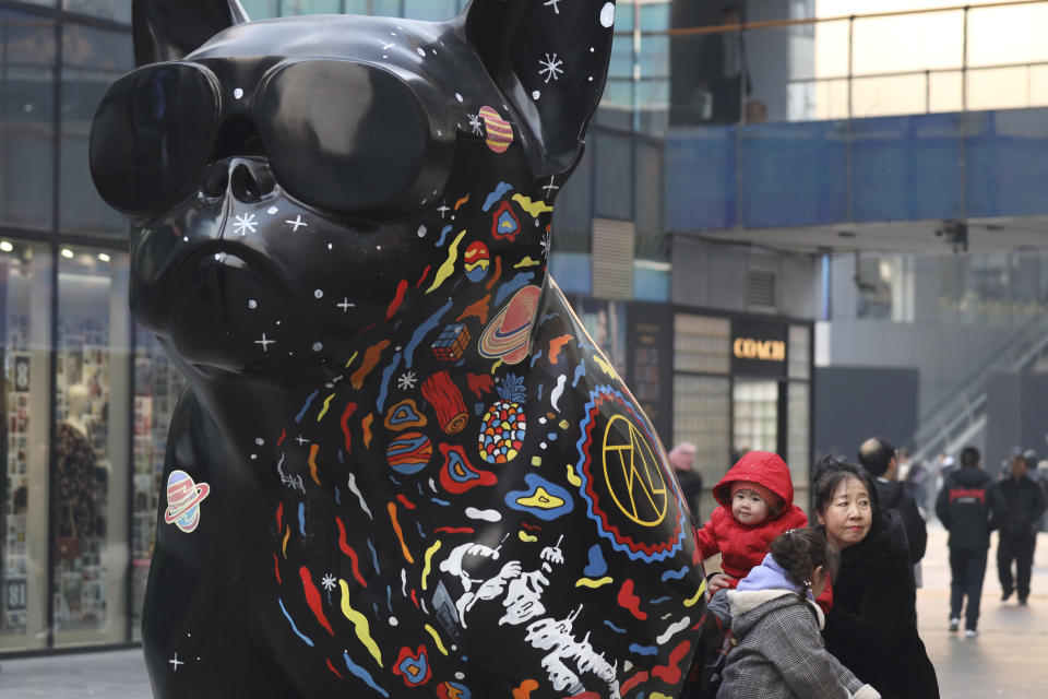 In this Thursday, Jan. 3, 2019, photo, a woman and children play near an art installation at a shopping mall in Beijing. A U.S. delegation led by deputy U.S. trade representative, Jeffrey D. Gerrish arrived in the Chinese capital ahead of trade talks with China. China sounded a positive note ahead of trade talks this week with Washington, but the two sides face potentially lengthy wrangling over technology and the future of their economic relationship. (AP Photo/Ng Han Guan)