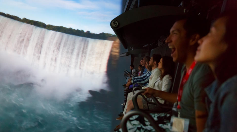 Families enjoy the FlyOver Canada screen while sitting in suspended chairs