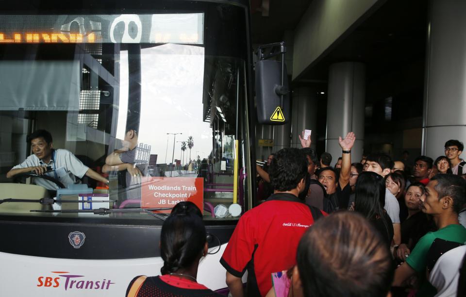 A commuter, among those who were affected by delays in bus services coming from Johor Bahru, shouts as he demands to be let into a bus travelling to Malaysia at the bus terminal at Singapore's Woodlands Checkpoint August 1, 2014. According to local media, Malaysian buses ferrying workers and school children have staged a strike early on Friday, at the Johor Bahru checkpoint to protest against new toll charges. REUTERS/Edgar Su (SINGAPORE - Tags: TRANSPORT CIVIL UNREST POLITICS BUSINESS EMPLOYMENT)