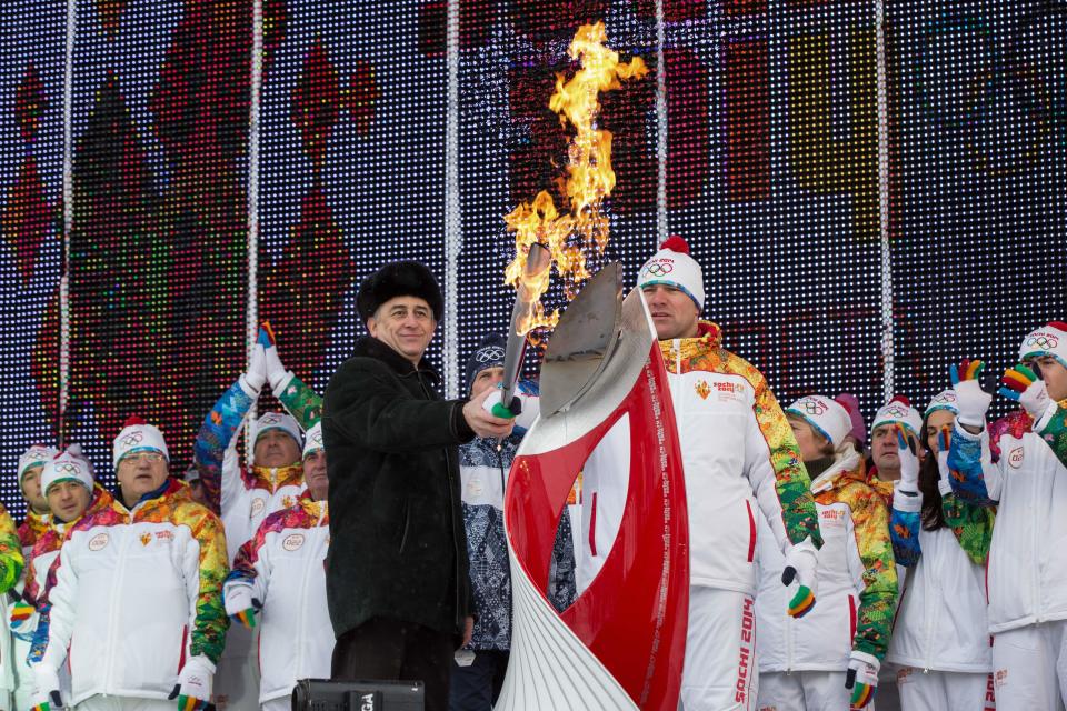 In this photo provided by Olympictorch2014.com, Olympic wrestling champion Aslanbek Khushtov, right, and acting head of Kabardino-Balkaria Yuri Kokov light Olympic flame during a welcome ceremony of the Olympic torch relay in Nalchik, the regional capital of Kabardino-Balkaria province, southern Russia, Thursday, Jan. 30, 2014. The 65,000-kilometer (40,389 mile) Sochi torch relay, which started on Oct. 7, is the longest in Olympic history. The torch has traveled to the North Pole on a Russian nuclear-powered icebreaker and has even been flown into space. (AP Photo/ Olympictorch2014.com)