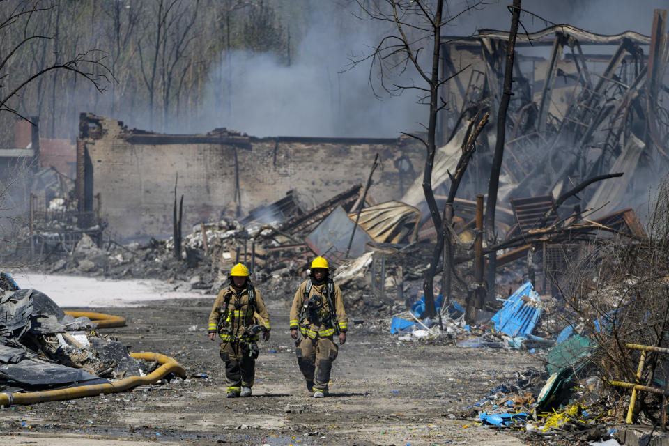Firefighters walk out of the site of an industrial fire in Richmond, Ind., Wednesday, April 12, 2023. Authorities urged people to evacuate if they live near the fire. The former factory site was used to store plastics and other materials for recycling or resale. (AP Photo/Michael Conroy)