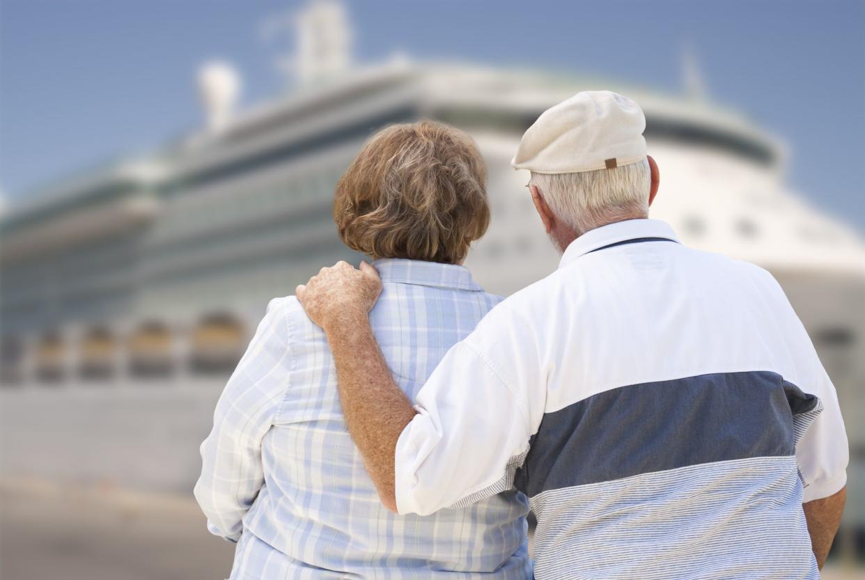 Senior Couple On Shore Facing and Looking at Docked Cruise Ship.